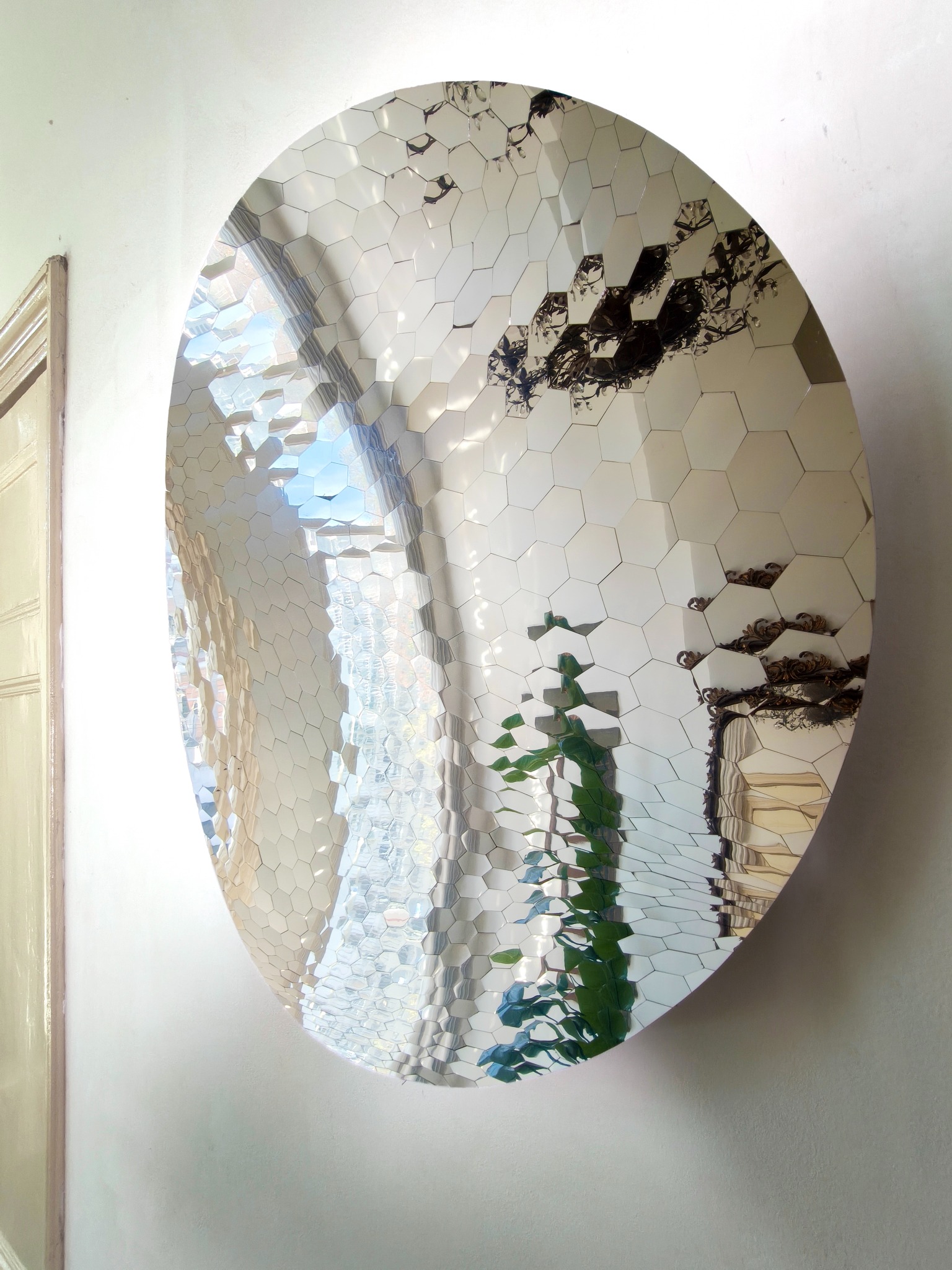 Large curved mirror assembled from irregular hexagonal reflective pieces