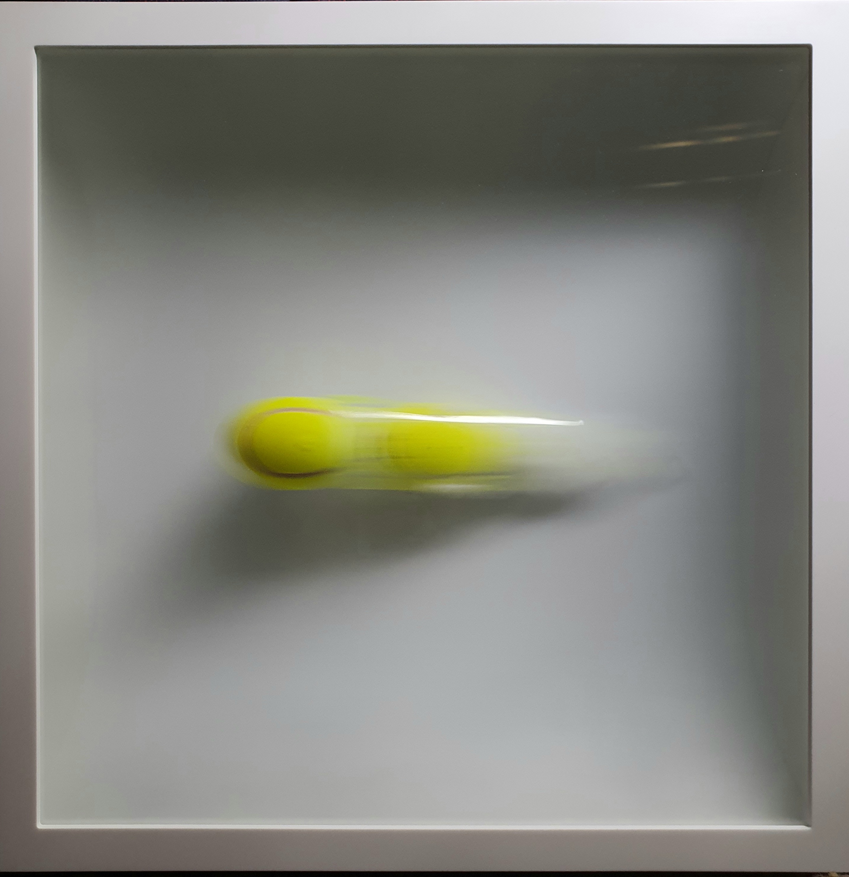 Tennis ball leaving a blurred trail inside a white frame
