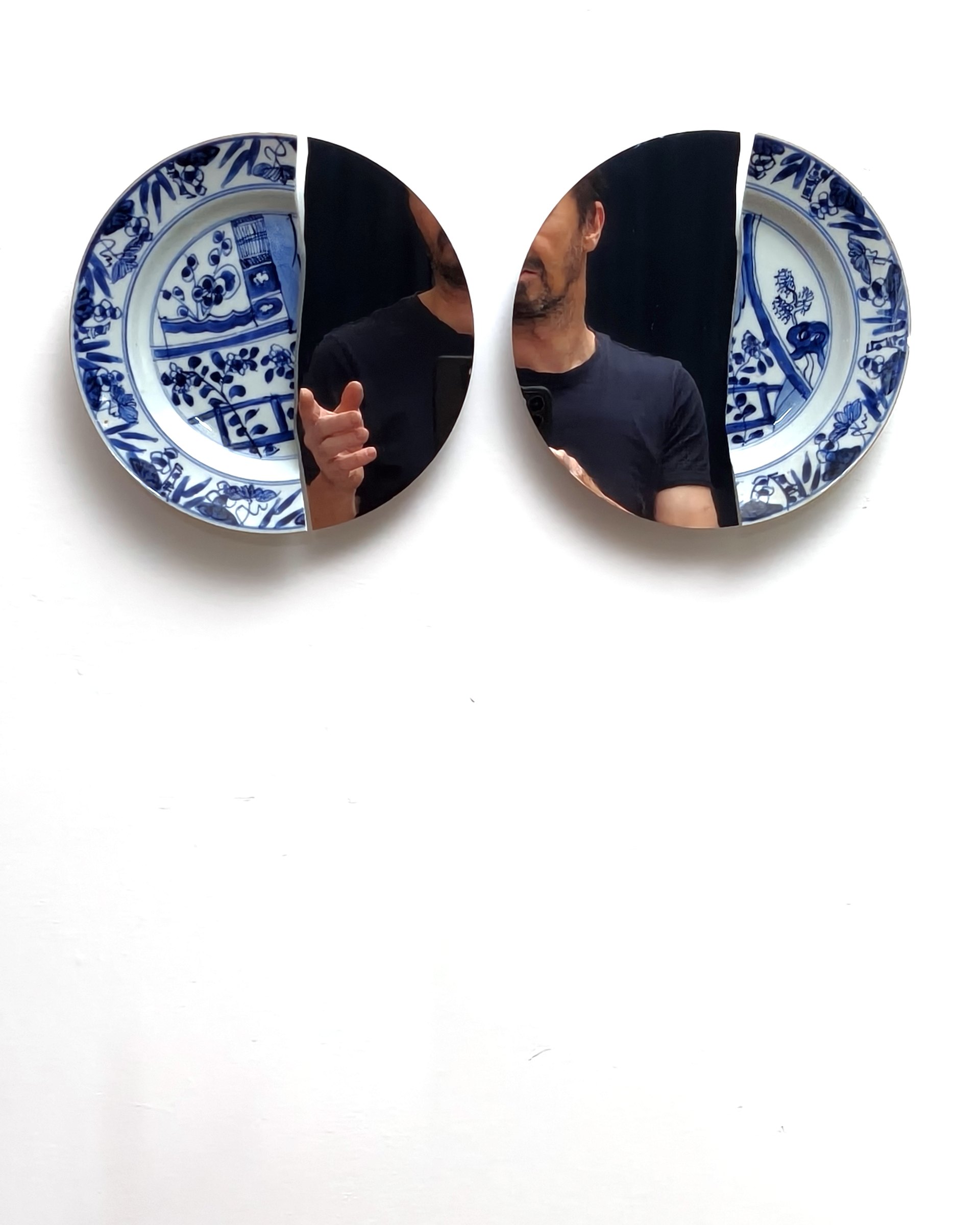 Viewer reflected in two blue and white mirror plates
